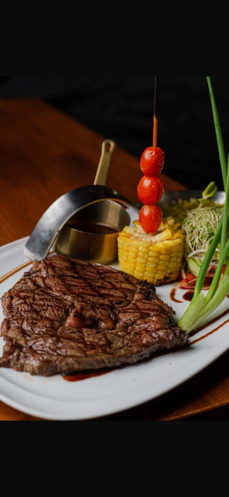 Grilled steak plated with corn, cherry tomatoes and sauce at EAT Bar and Grill in Karon Phuket